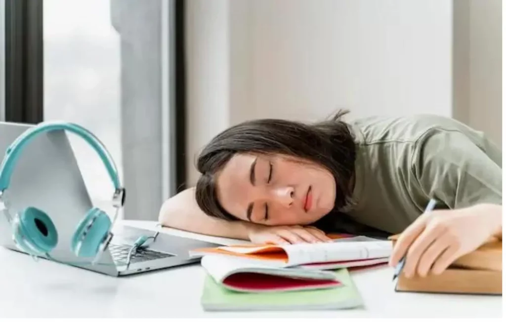 Seorang wanita yang tertidur saat mengerjakan tugas