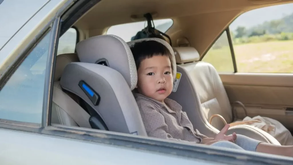 Balita duduk di kursi khusus anak pada baris kedua di dalam mobil dengan jendela terbuka