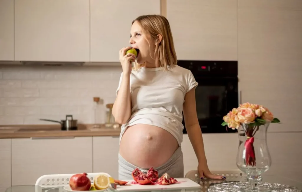 Seorang wanita hamil yang sedang memakan buah